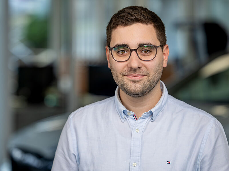 Kaltenbach Gruppe – Ein Mann mit kurzen braunen Haaren und Brille, der ein hellblaues Button-up-Hemd trägt, steht in einem Innenraum mit unscharfem Hintergrund in Kaltenbach Lennestadt. Er blickt in die Kamera und lächelt leicht. – BMW, MINI, KIA, BMW Motorrad & Honda Motorrad Partner in NRW