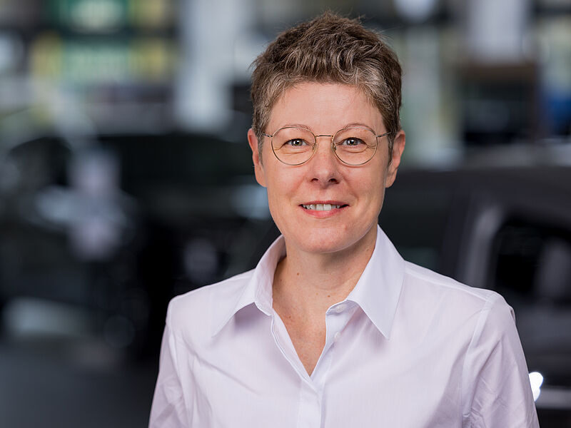 Kaltenbach Gruppe – Eine Person mit kurzem Haar und Brille, die ein weißes Hemd mit Kragen trägt, lächelt in die Kamera. Der unscharfe Hintergrund deutet auf einen Innenraum hin, möglicherweise in der Kaltenbach Zentrale. – BMW, MINI, KIA, BMW Motorrad & Honda Motorrad Partner in NRW