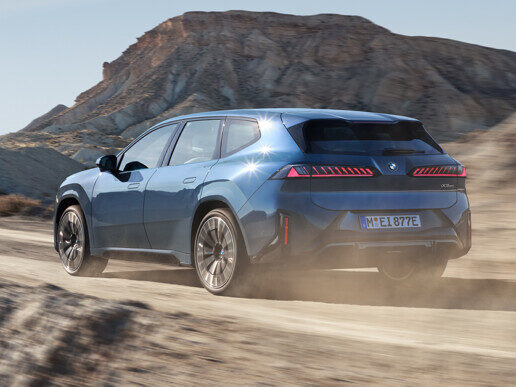 Kaltenbach Gruppe – Ein BMW iX3 Elektro-Geländewagen fährt über einen unbefestigten Weg, sein blaues Äußeres hebt sich von der rauen Landschaft ab. – BMW, MINI, KIA, BMW Motorrad & Honda Motorrad Partner in NRW