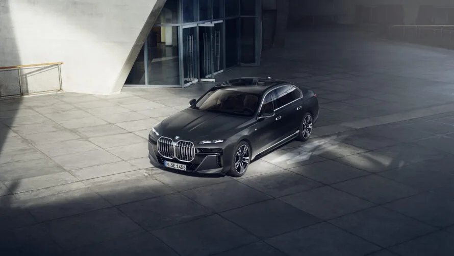Kaltenbach Gruppe – Eine elegante, schwarze BMW Limousine - Teil der neuesten BMW Angebote Rewe - steht auf einem großen, leeren Betonplatz vor einem modernen Glasgebäude, beleuchtet von einem Sonnenstrahl. – BMW, MINI, KIA, BMW Motorrad & Honda Motorrad Partner in NRW