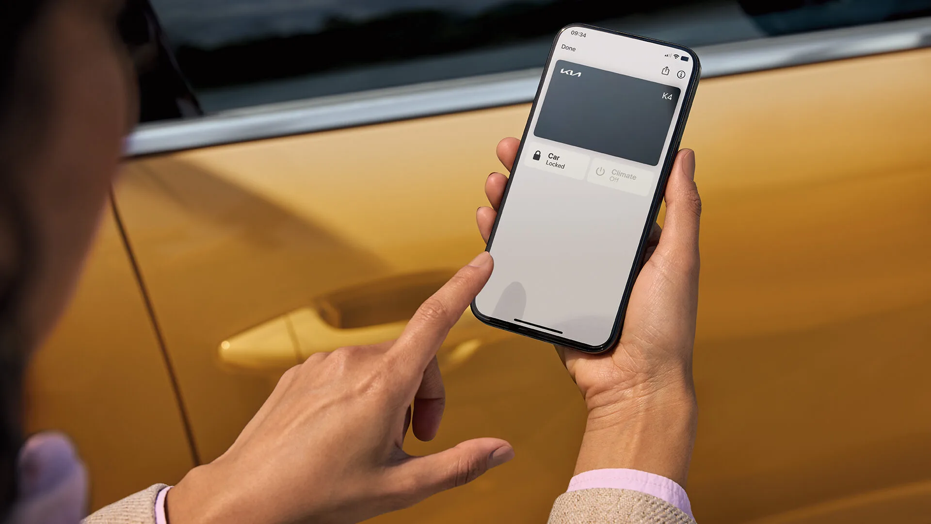 Eine Hand hält ein Smartphone mit dem Kia Digital Key an die Tür eines gelben Kia K4