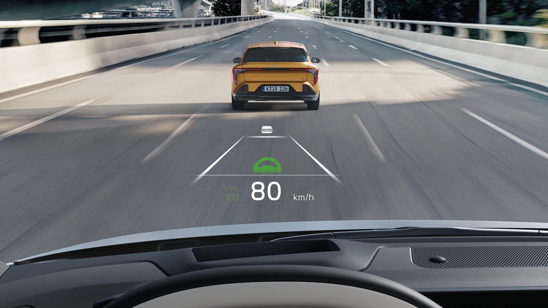 Blick durch die Windschutzscheibe: Das Head-up Display zeigt 80 km/h, voraus fährt ein gelber Kia K4