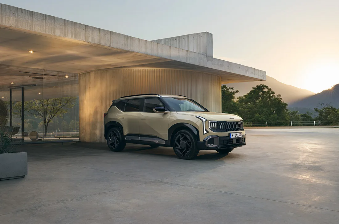 Der neue Kia Seltos vor einem modernen Glashaus bei Sonnenuntergang